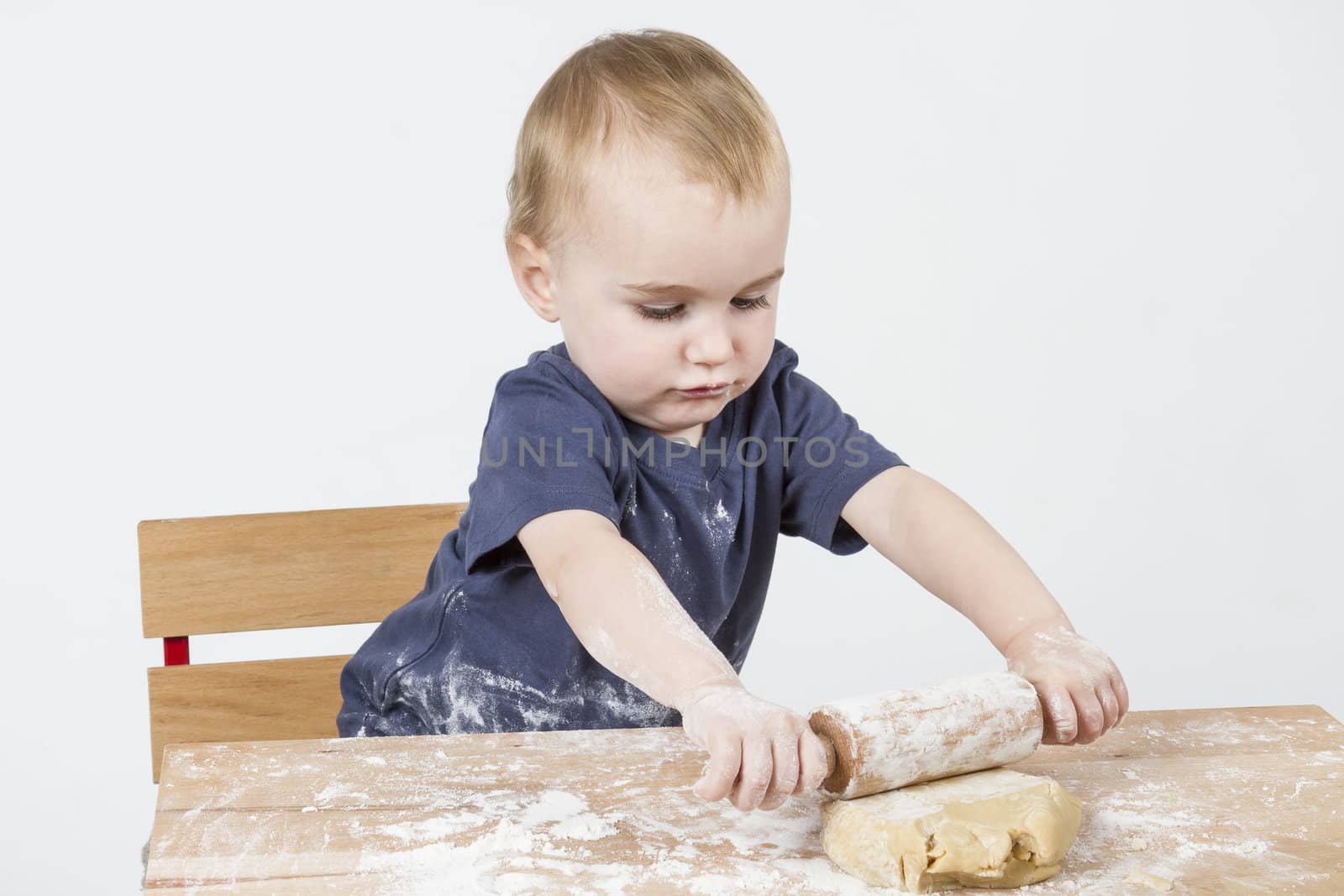 young child making cookies on small wooden desk