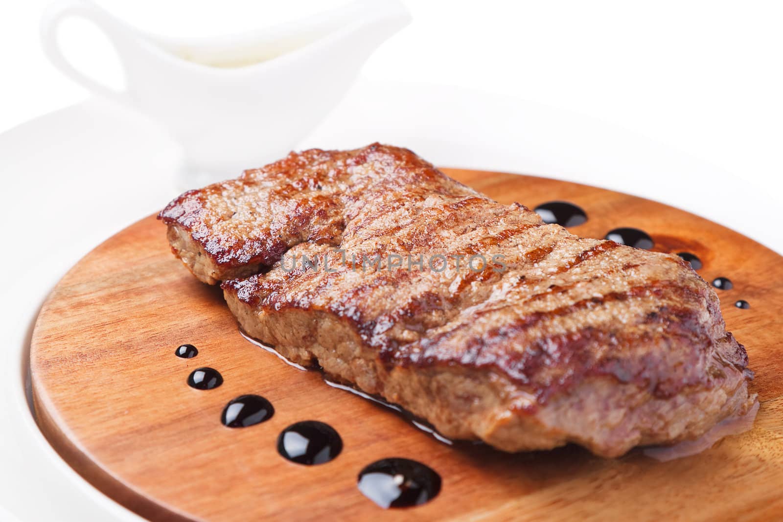a piece of grilled meat on a wooden board on a white background