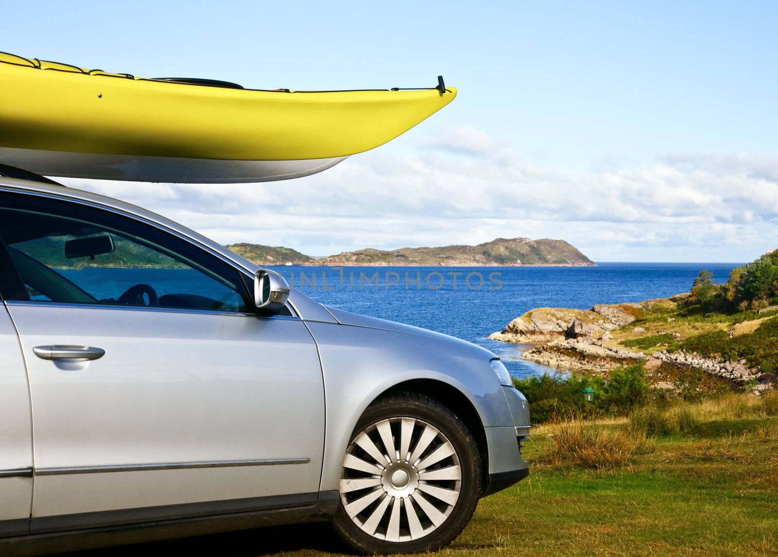 Car with yellow kayak at ocean shore