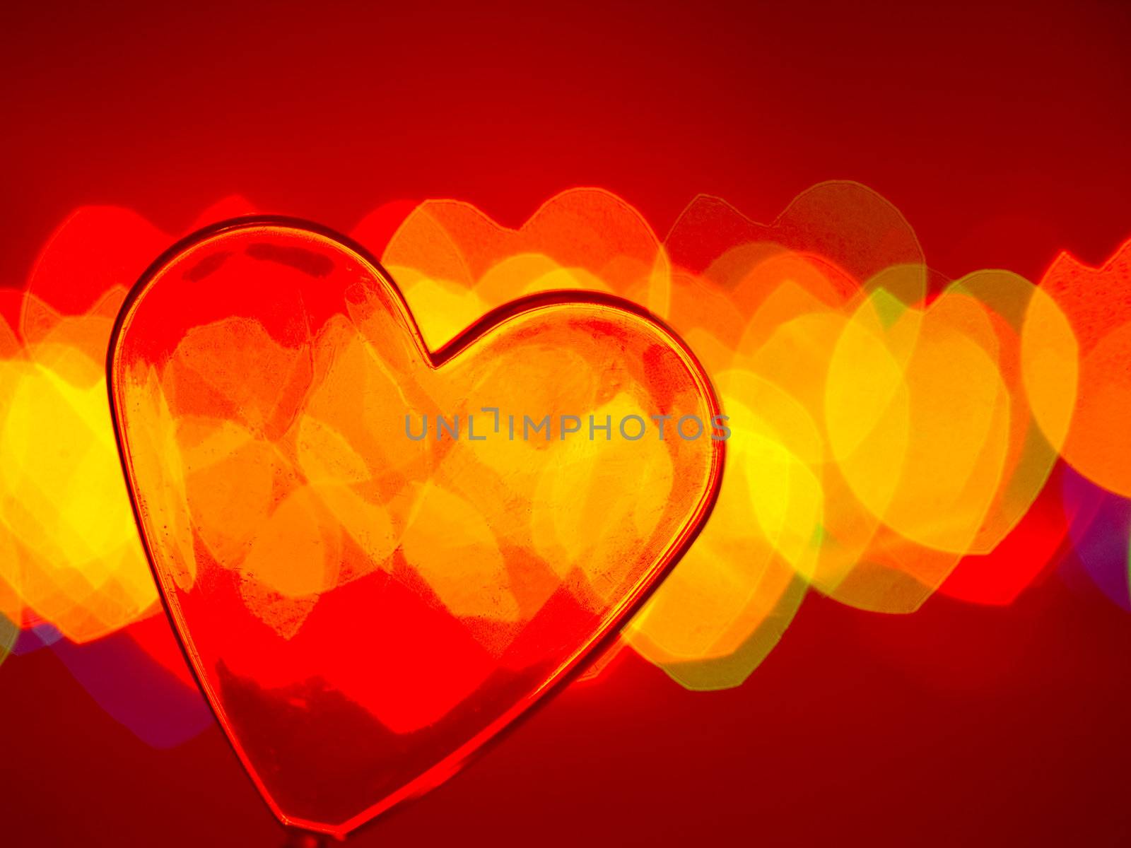 Red transparent plastic heart with blured lights in background, very shallow DOF