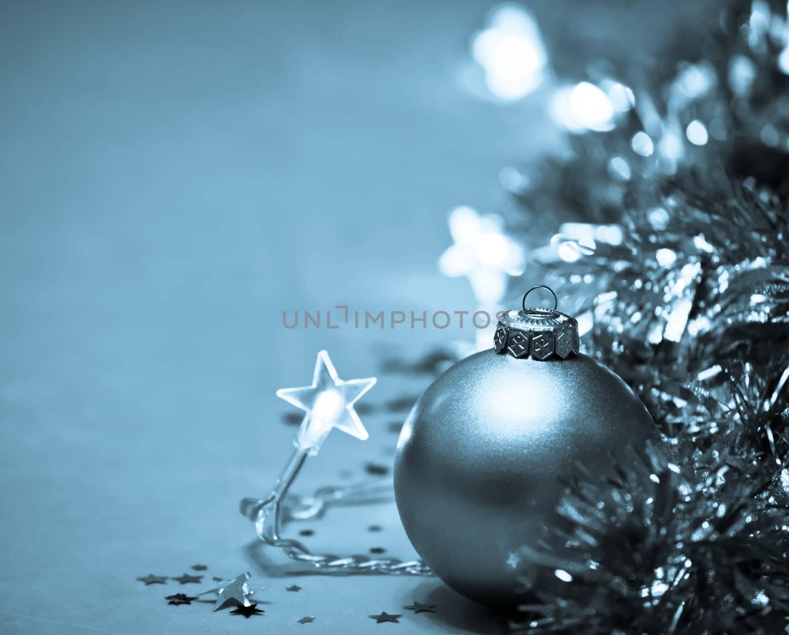 Golden Christmas bauble with star-shaped lights and tinsel, very shallow DOF