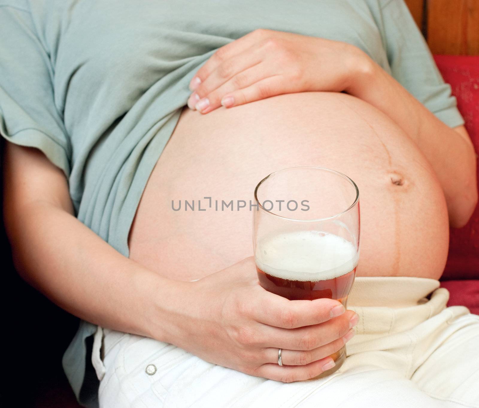 Young pregnant woman holding glass of beer