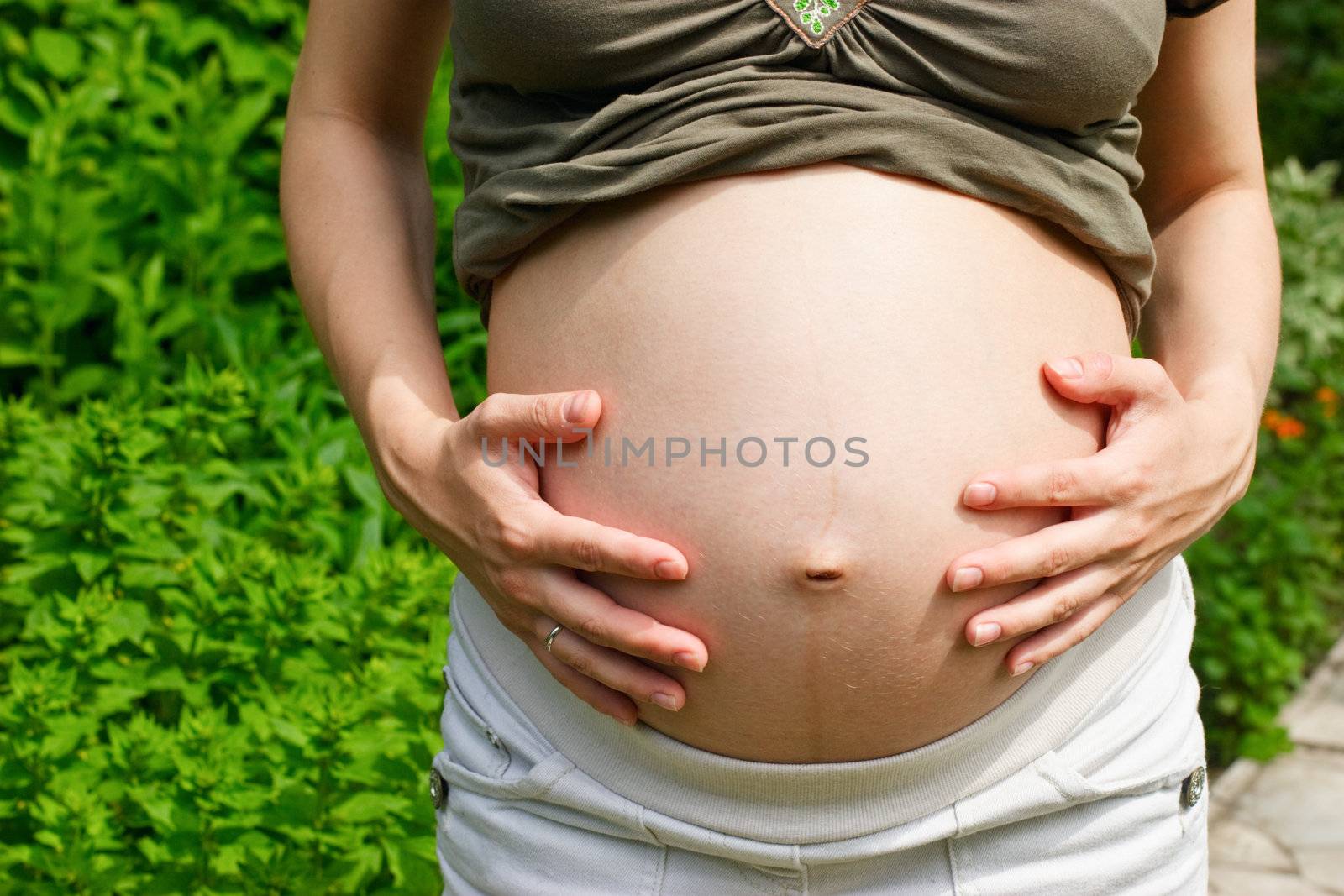 Young pregnant woman taking a sunbath in a summer garden