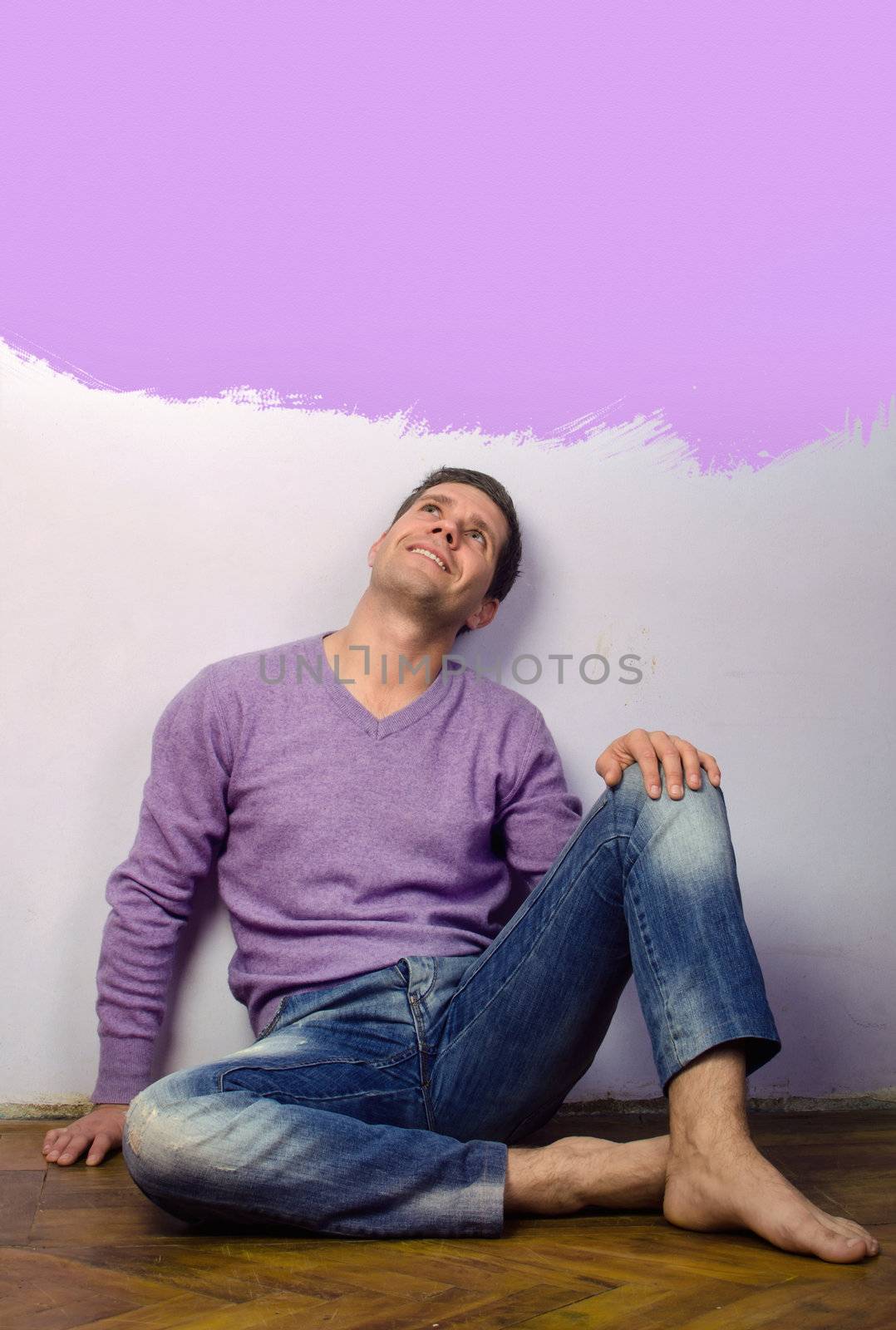 Young adult  sitting on hardwood floor in home smiling 