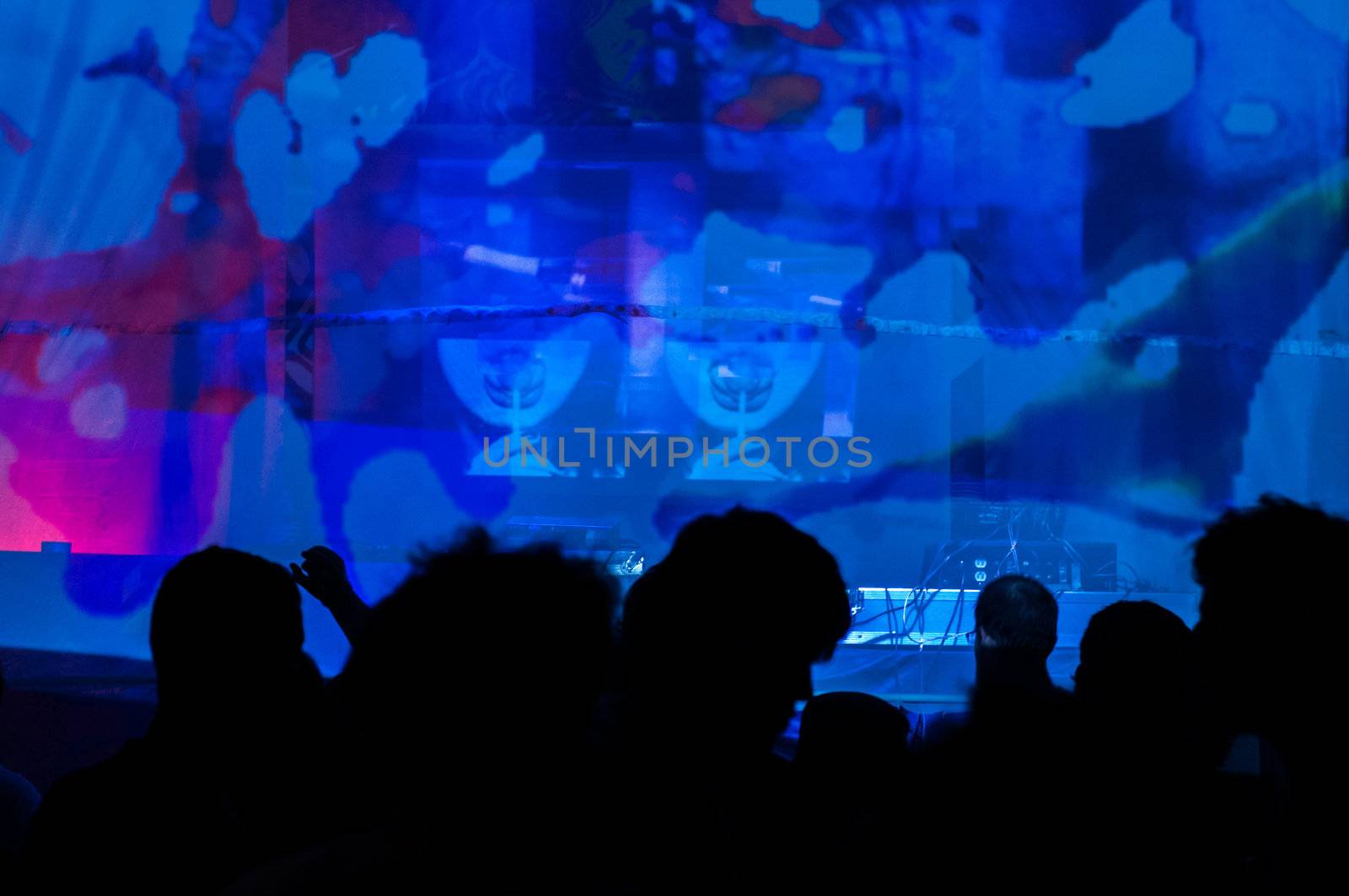 Silhouettes dancing in a club set against a blue backdrop.