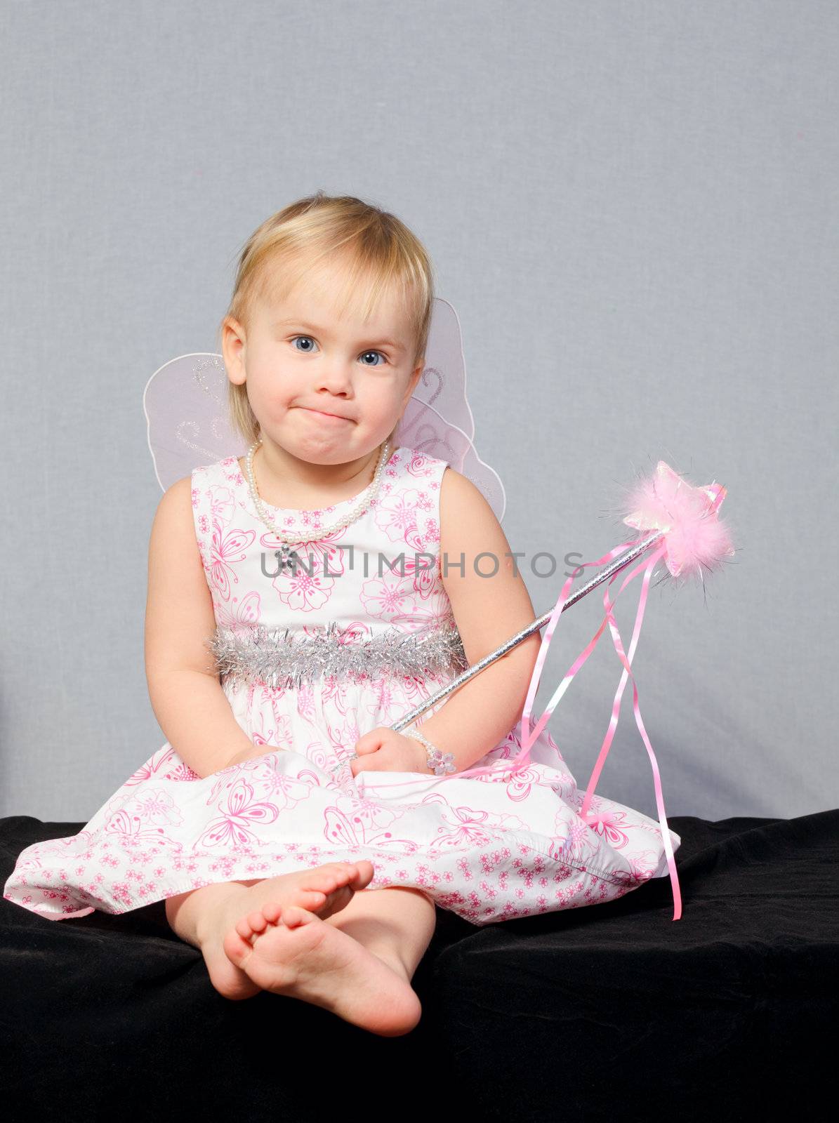 Portrait of cute little girl wearing wings holding wand