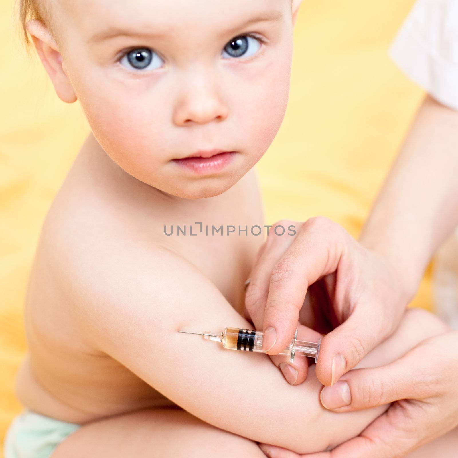 Doctor giving a child an intramuscular injection in arm, focus on syringe