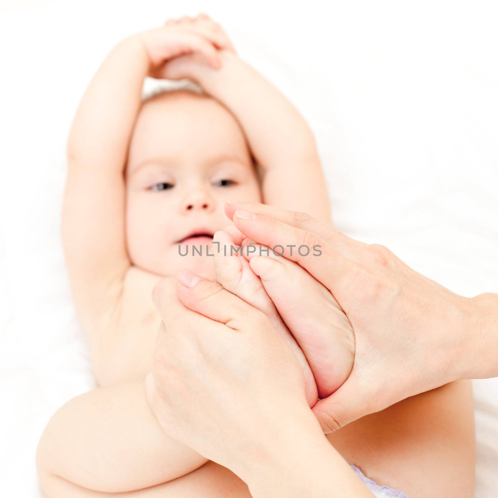 Masseur massaging little baby's feet, shallow focus