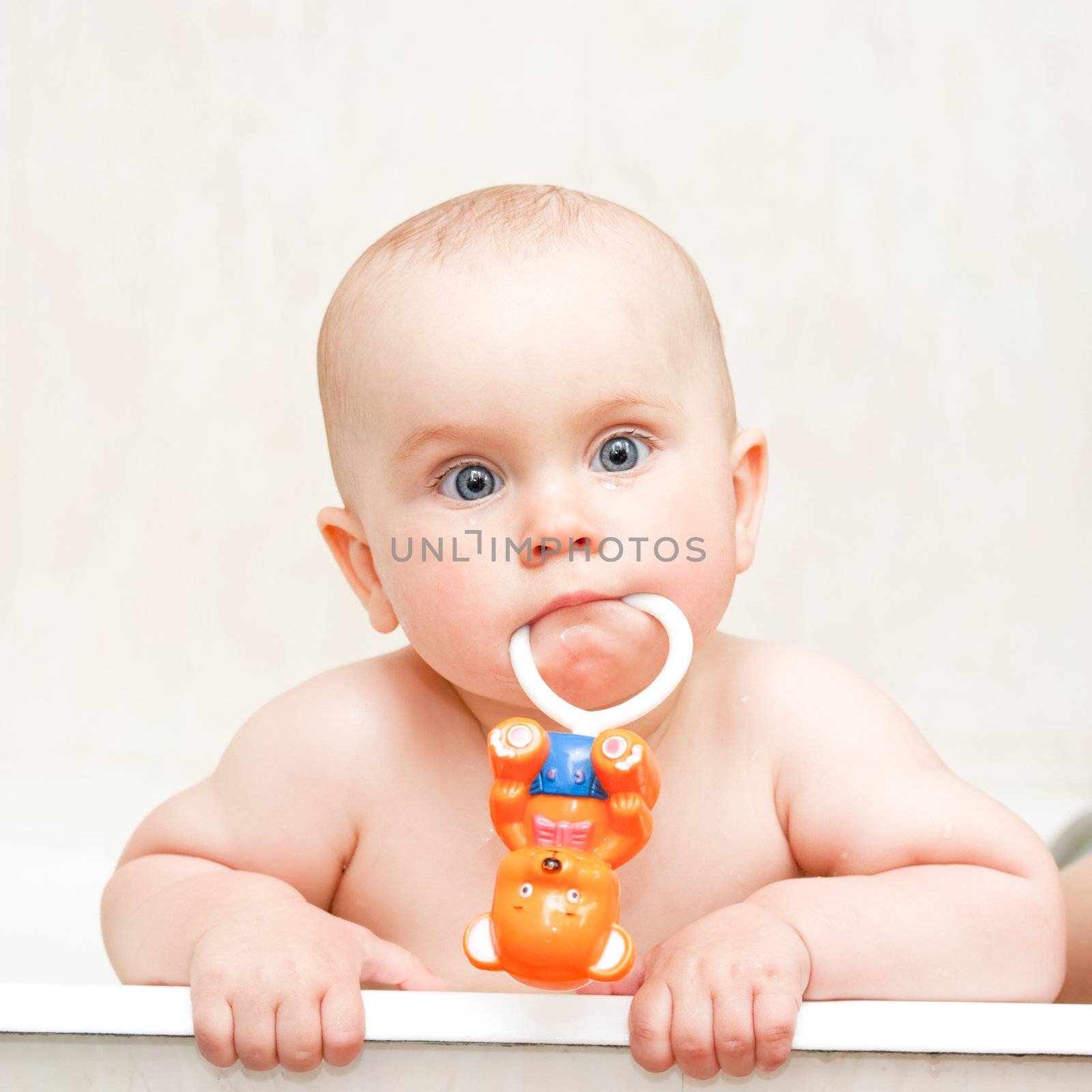 Little baby girl bathing with rattle
