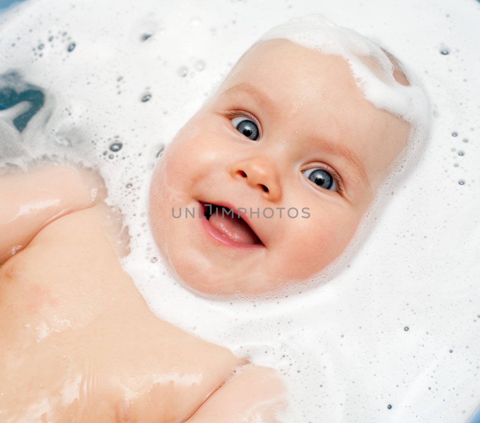 Little baby girl bathing in soapsuds
