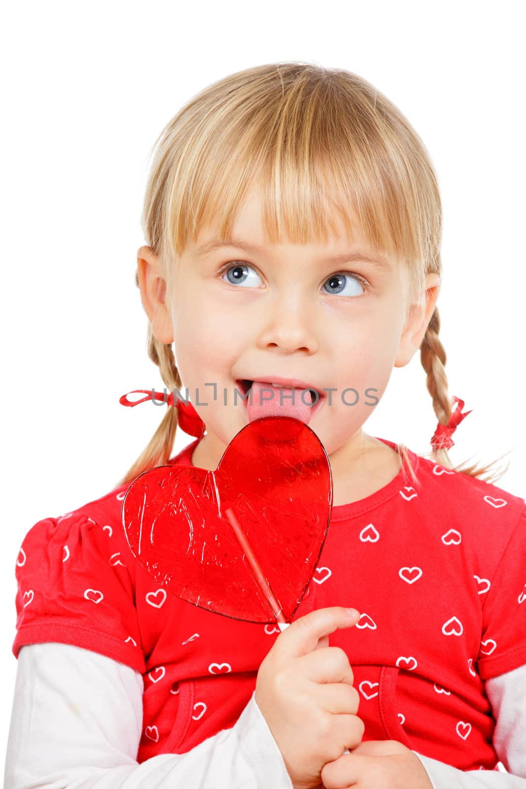 Cute little girl licking big red heart shaped lolly pop candy