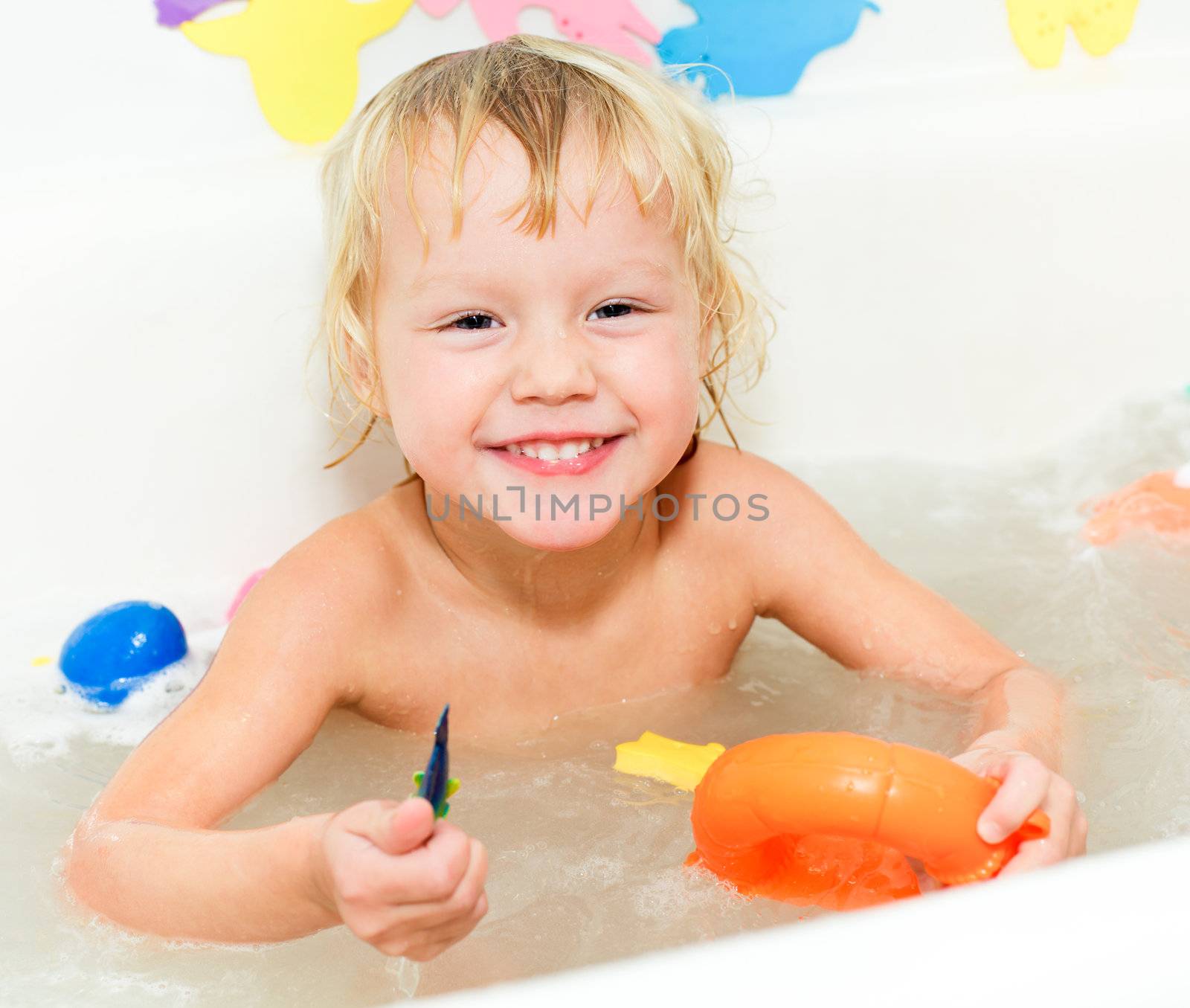 Cute little girl bathing with toys