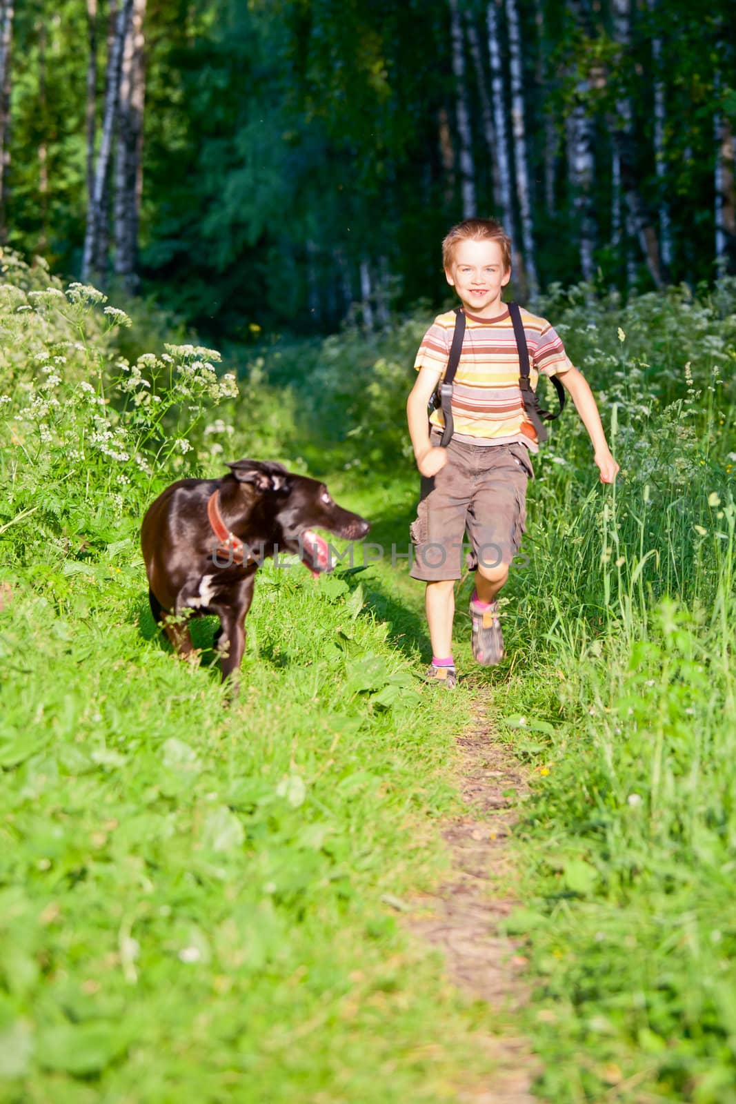 Happy cute boy running with black dog