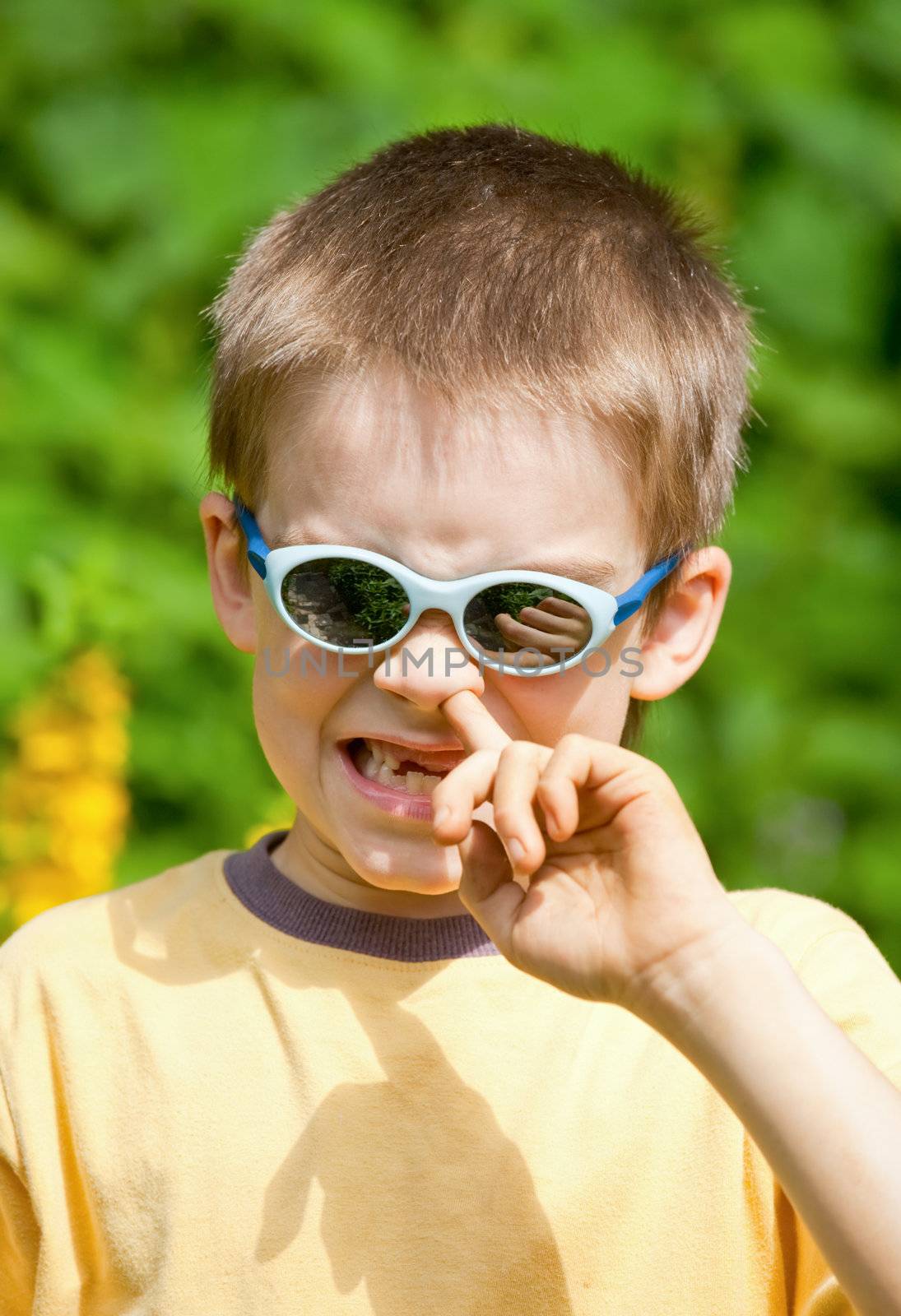 Portrait of a young boy wearing sunglasses picking his nose
