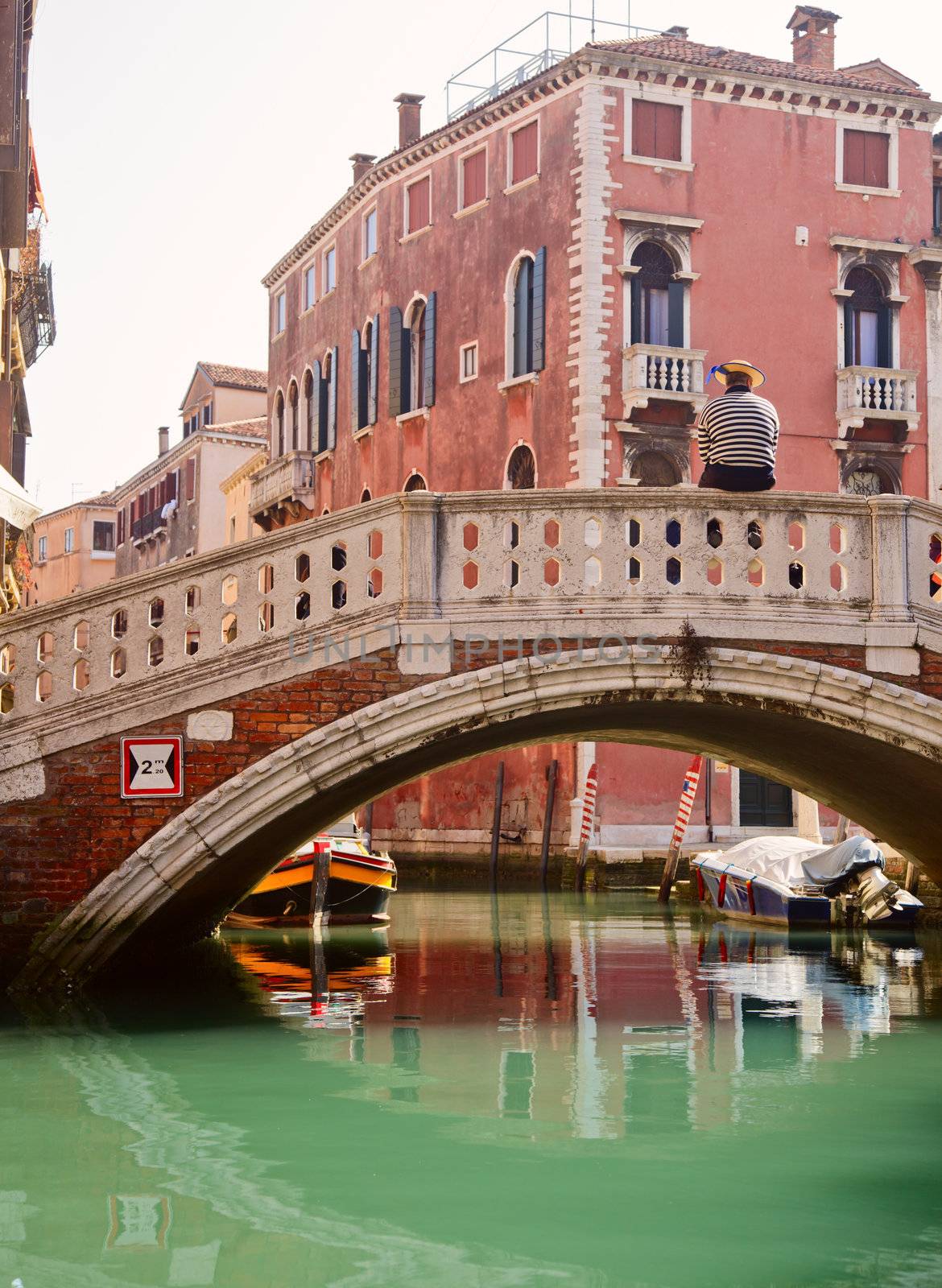 Lonely Gondolier sitting on a bridge waiting for tourists in Venice