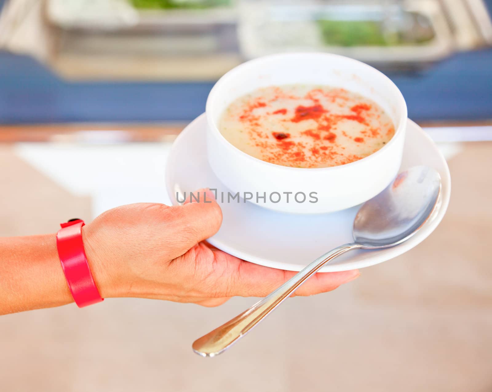 Young woman wearing all-inclusive bracelet holding plate with soup