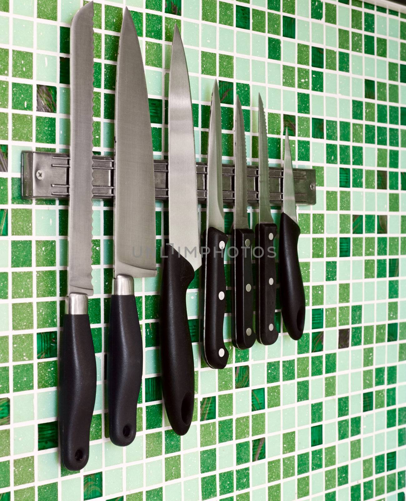 Kitchen knives on green mosaic wall