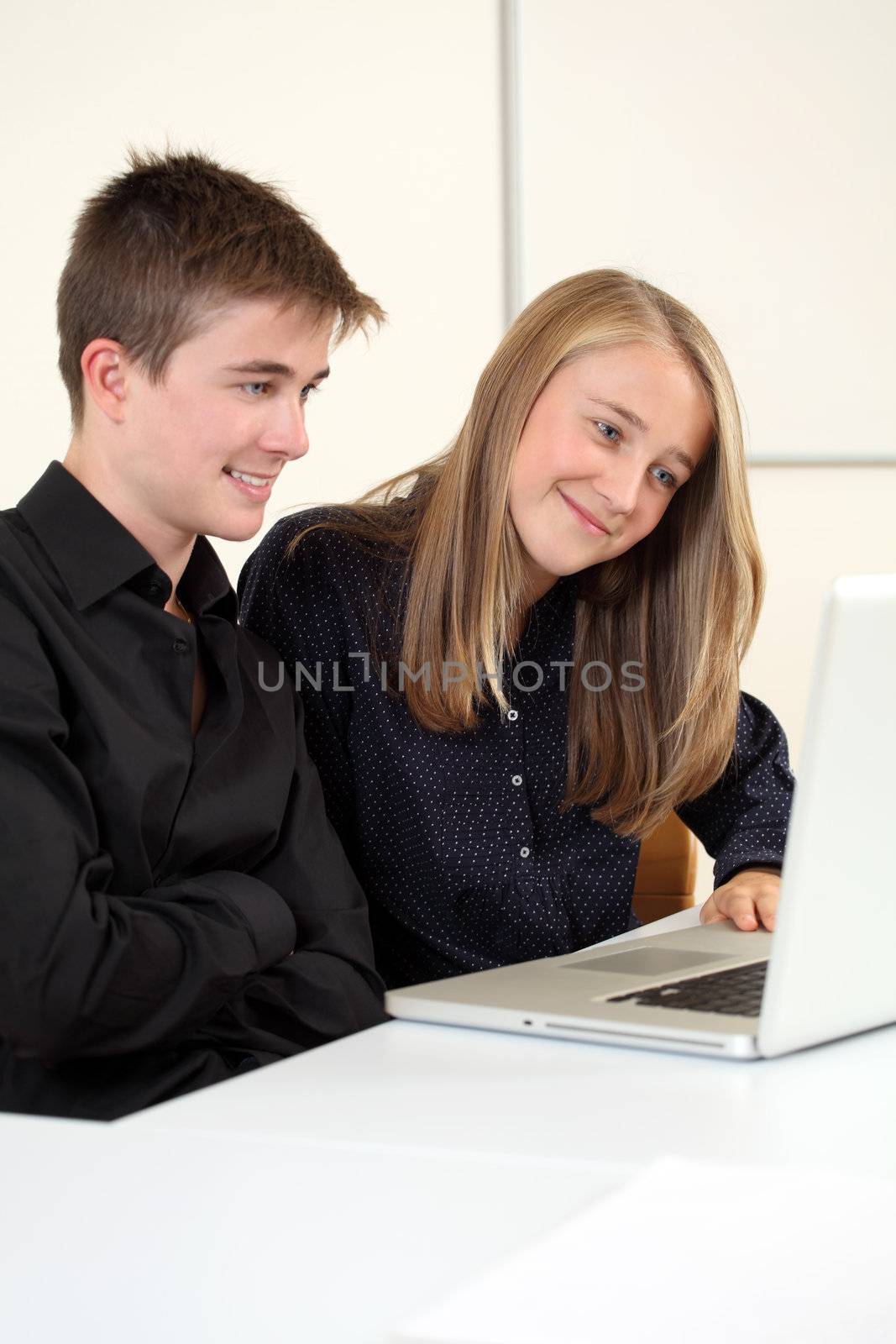 Photo of two students in their class working on a laptop.