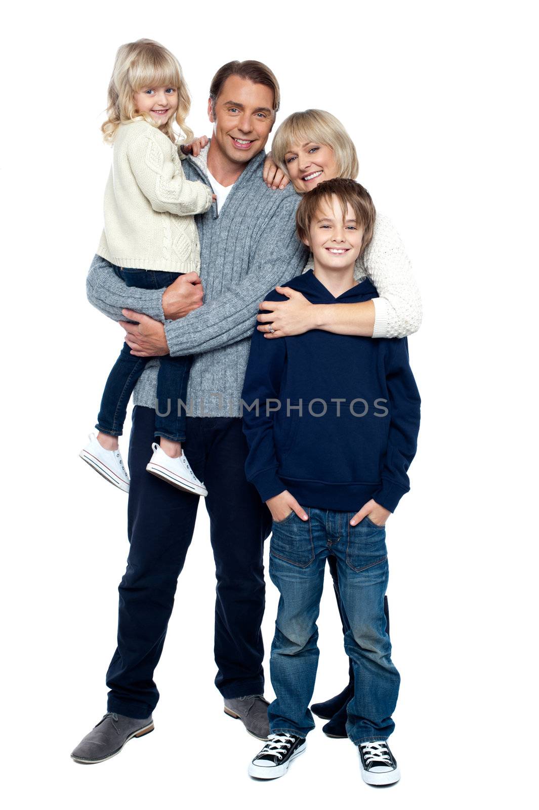 Affectionate family of four posing in winter outfits. Full length studio shot.