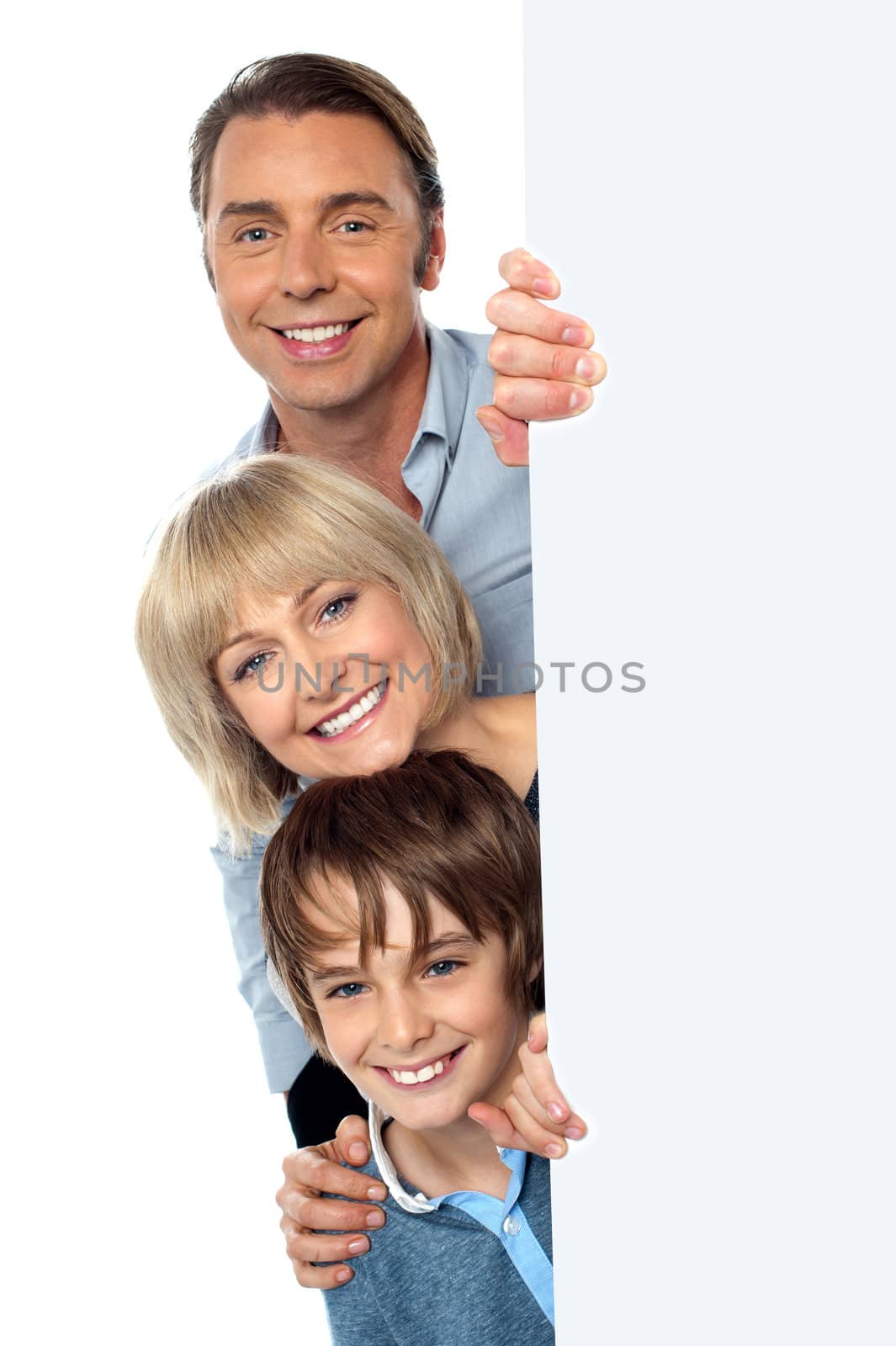Smiling trio of a father, mother and son peeking by stockyimages