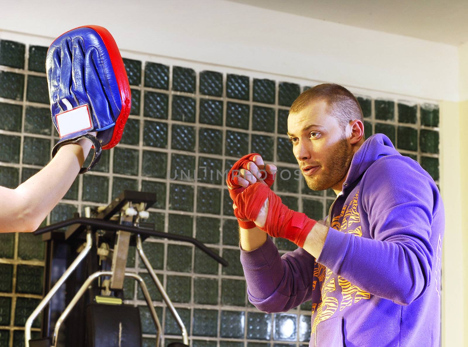 young adult man boxing in gym with his trainer