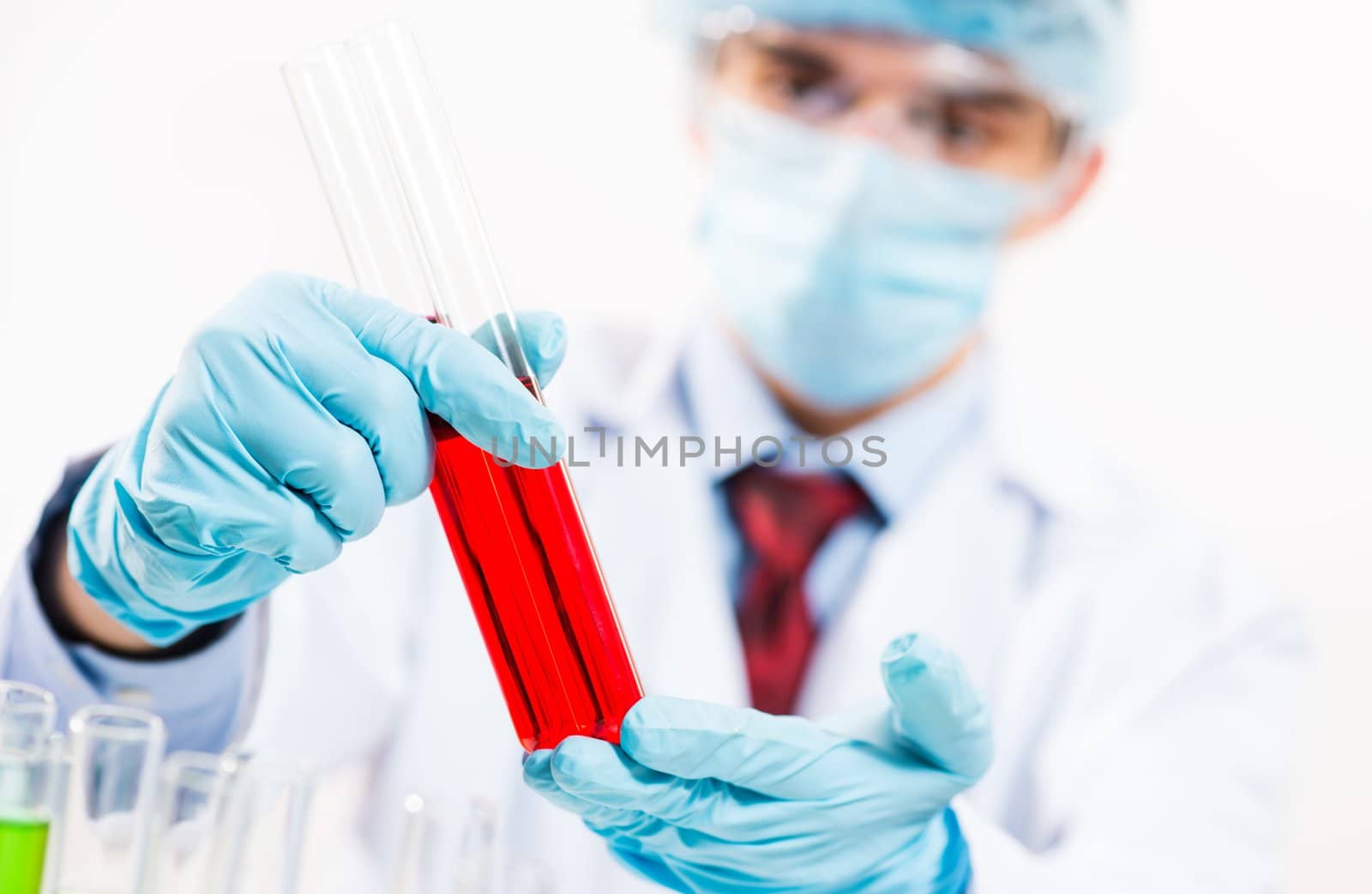 scientist working in the lab, in protective mask and cap, examines a test tube with liquid