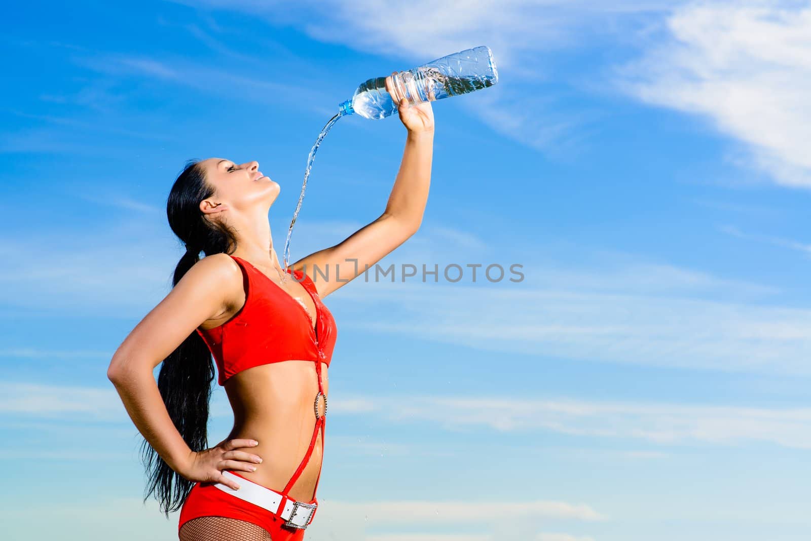 Young female sport girl in red uniform with a bottle of water
