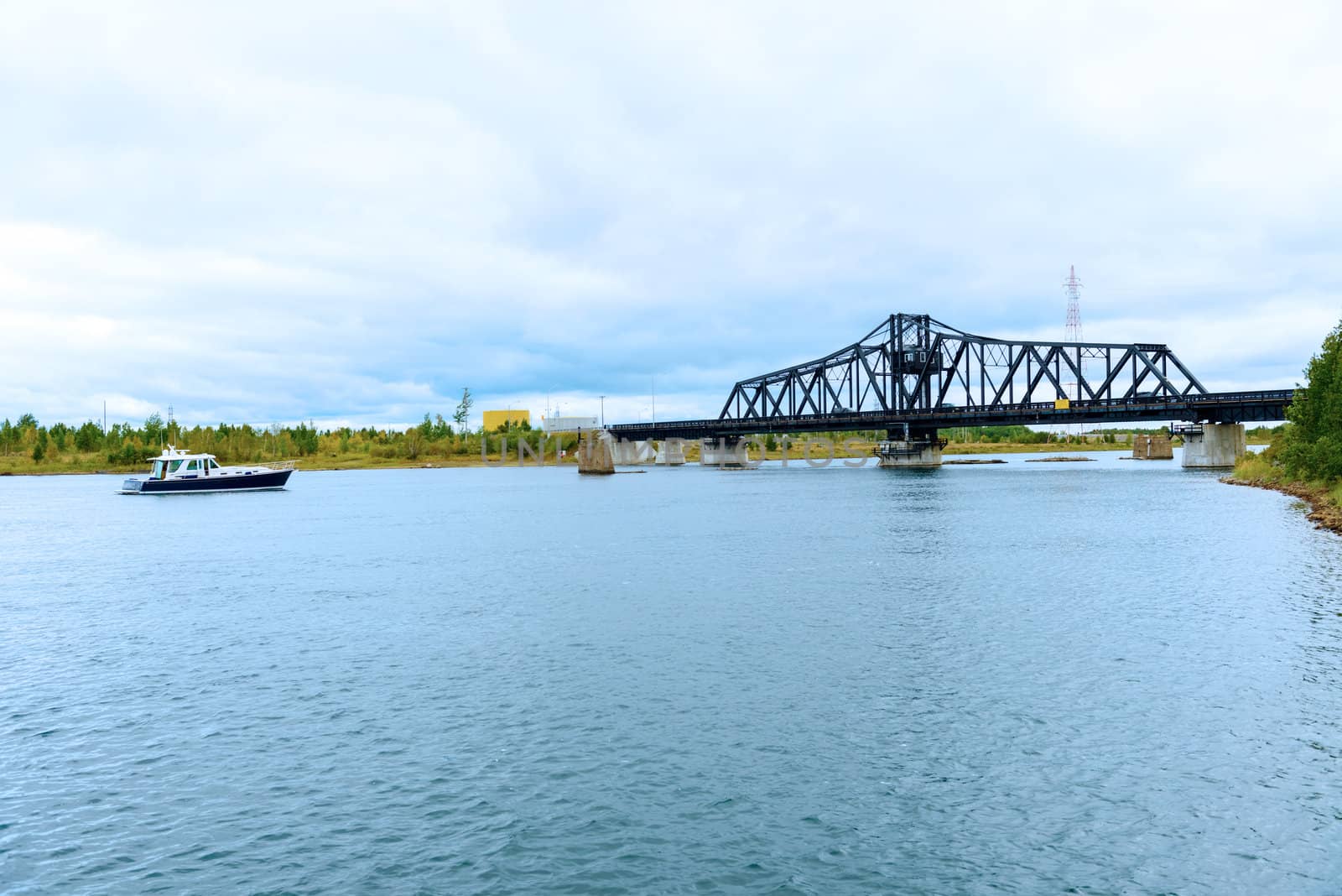 The bridge across a narrow channel separating Manitoulin Island from the much smaller Goat Island, forming the only land access. It consists of two 21 m (70 ft) deck plate girder approaches on the north end (Goat Island) and a single 18 m (60 ft) deck plate girder approach on the south end (Manitoulin Island), with a 112 m (368 ft) through swing bridge span. The swing bridge sits 5.3 m (17.5 ft) above mean water level, and provides a 48 m (160 ft) opening on either side of the central pier for water passage. Construction of the bridge was started by the Algoma Eastern Railway with the abutments and piers being built in 1912 and the bridge structure being erected in 1913. The Algoma Eastern Railway began operating trains across the bridge to the community of Little Current in October 1913. 