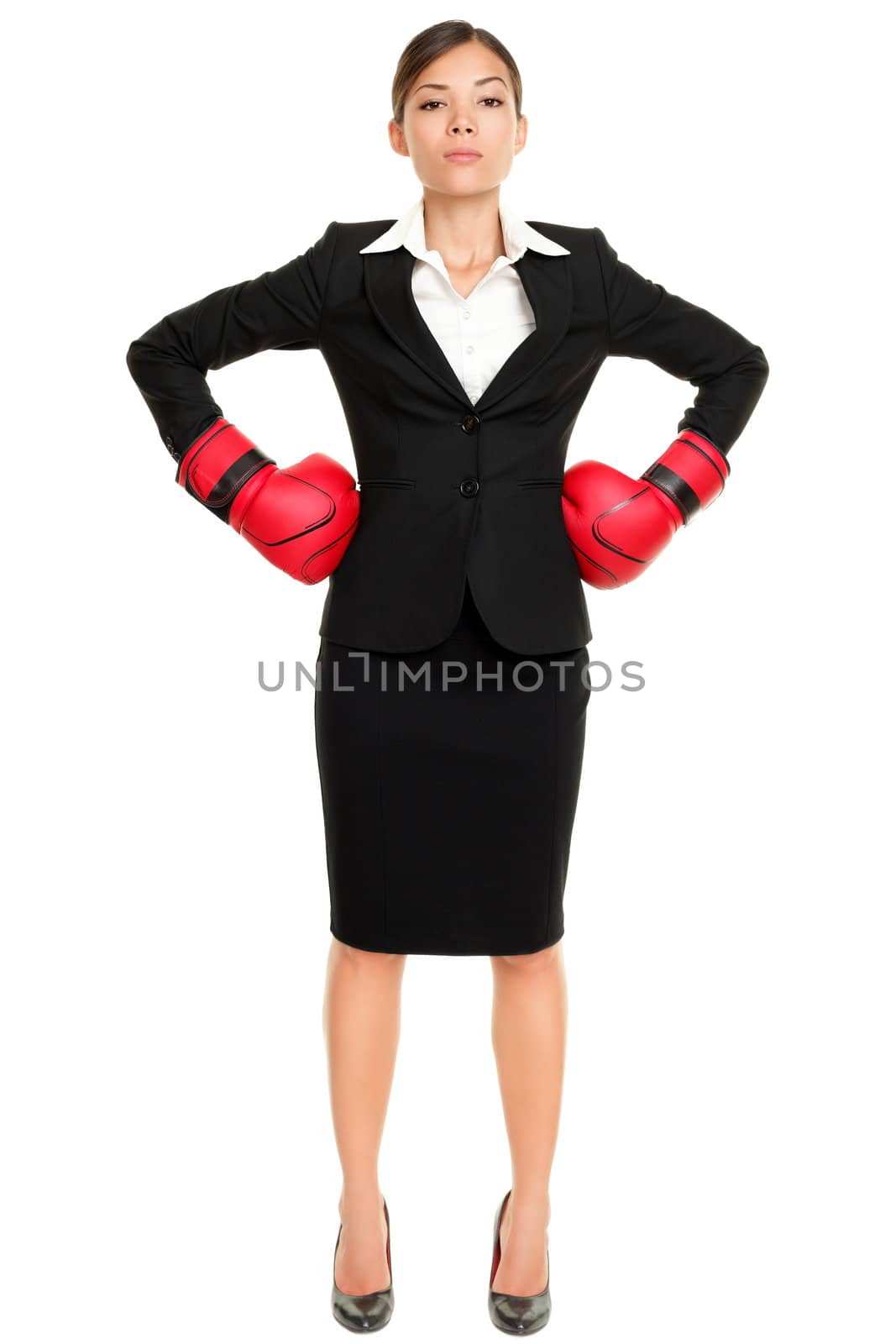 Strong business woman boss executive concept. Businesswoman standing intimidating wearing boxing gloves ready for the competition. Confident attitude by young mixed race female model in suit.