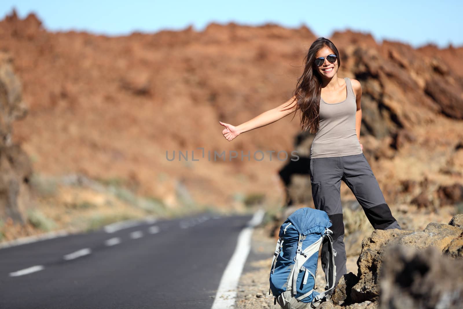 Travel woman hitchhiking. Beautiful young female hitchhiker by the road during vacation trip on Volcano Teide, Tenerife, Canary Islands.