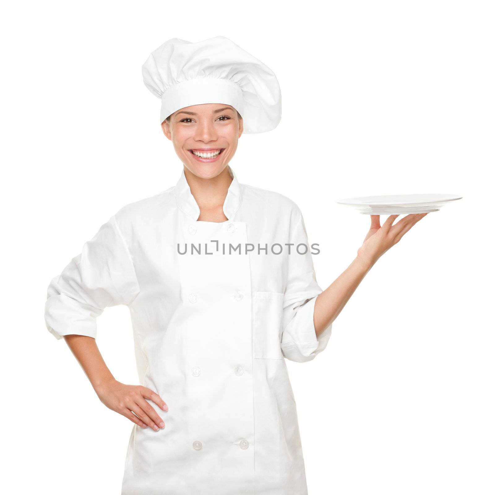 Chef showing empty plate. Happy smilng portrait of female in chef uniform and chef hat isolated on white background. Asian Caucasian woman model.