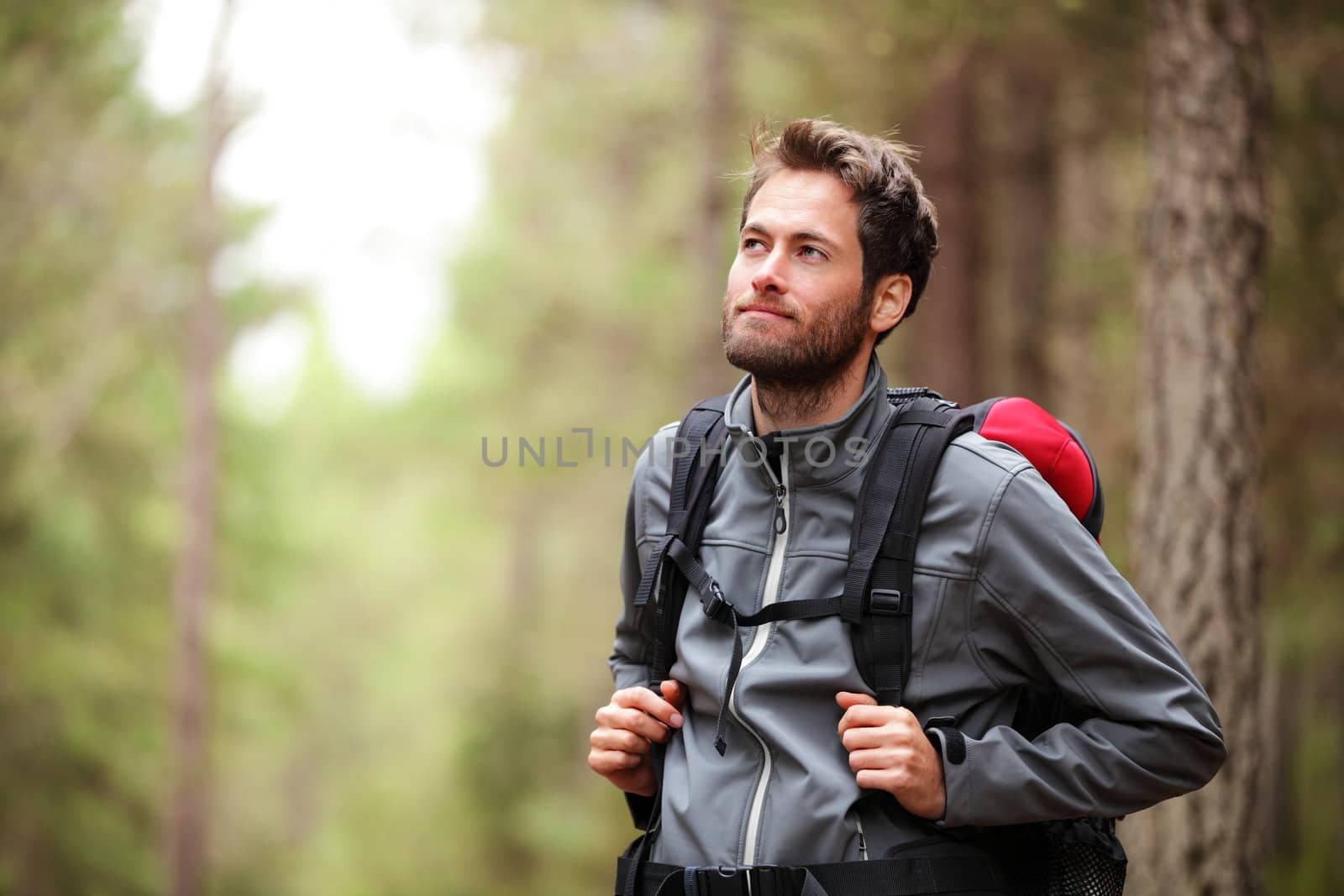 Hiker - man hiking in forest. Male hiker looking to the side walking in forest. Caucasian male model outdoors in nature.