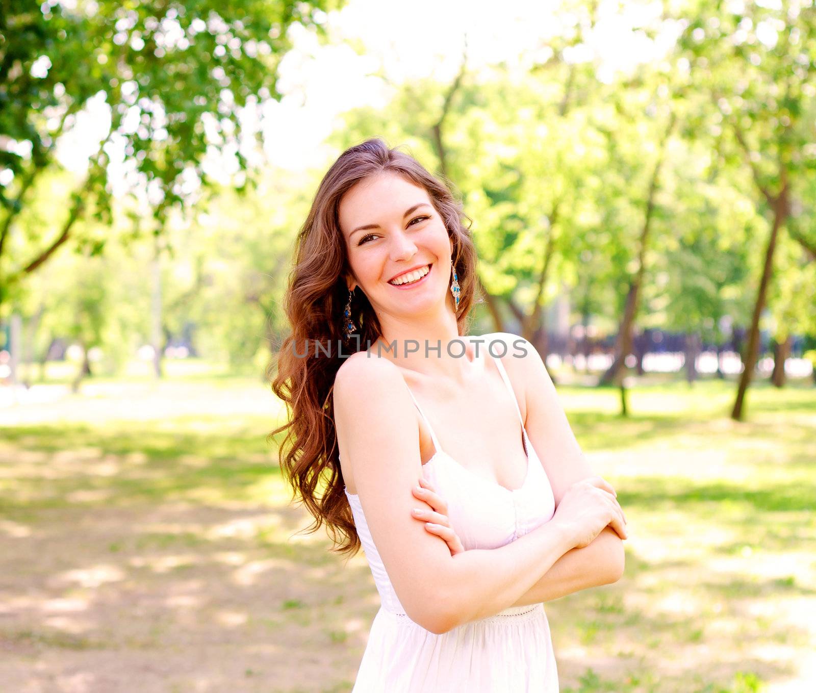 Portrait of an attractive woman in the park, crossed her arms and smile