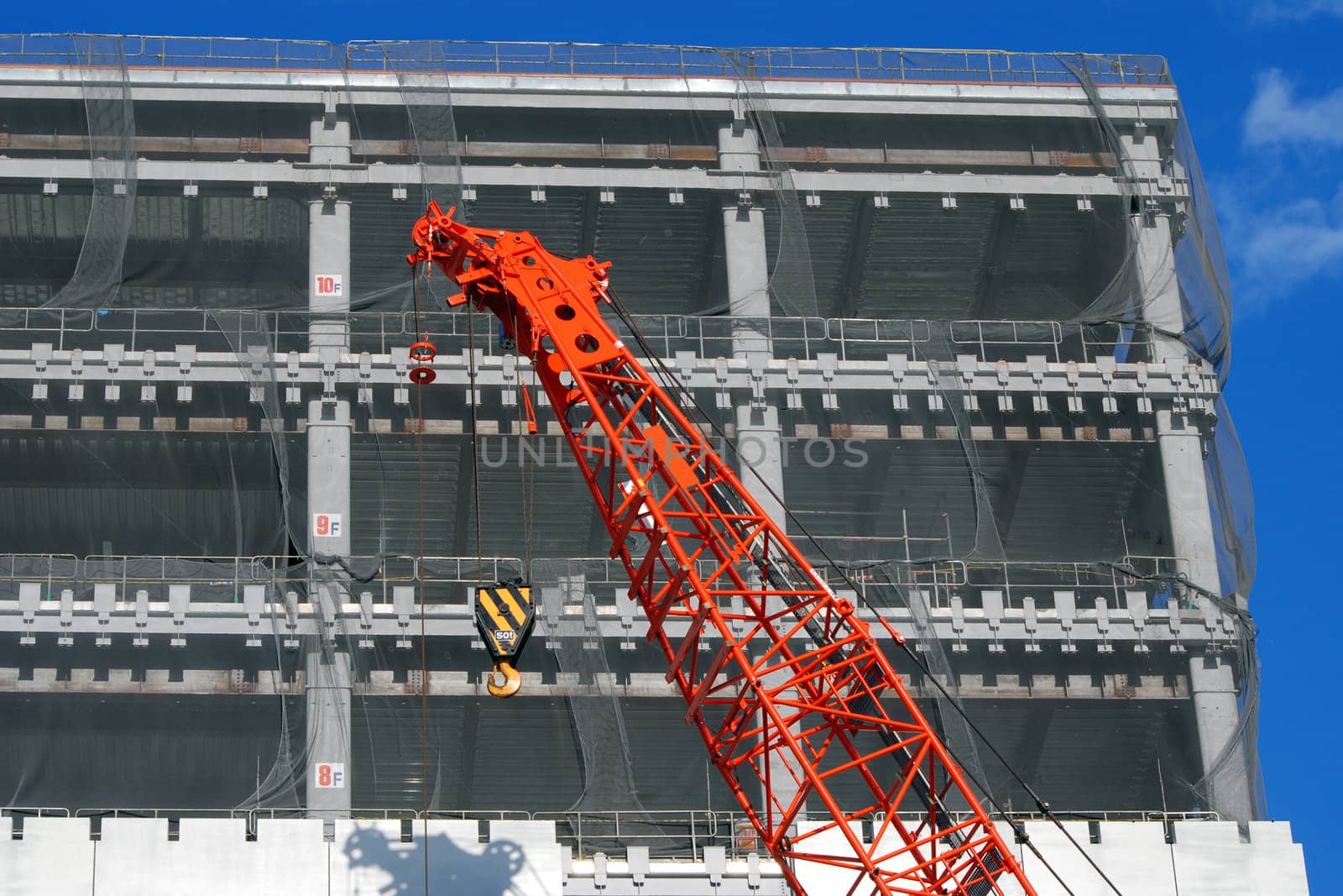 construction site with rising up building and red crane foreground
