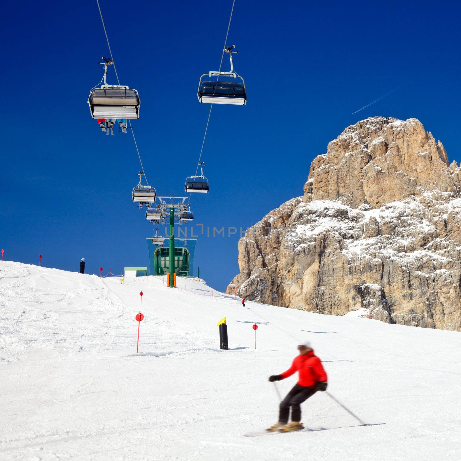 Skier going down the slope under ski lift at Sella Ronda ski route in Italy