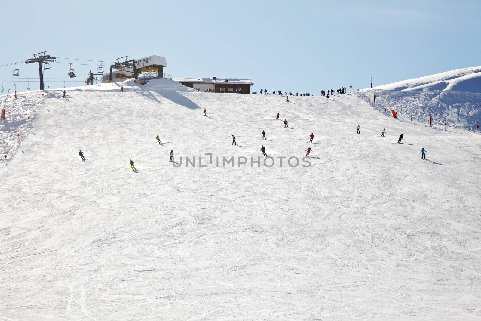 Skiers and snowboarders going down the slope at Val Di Fassa ski resort in Italy