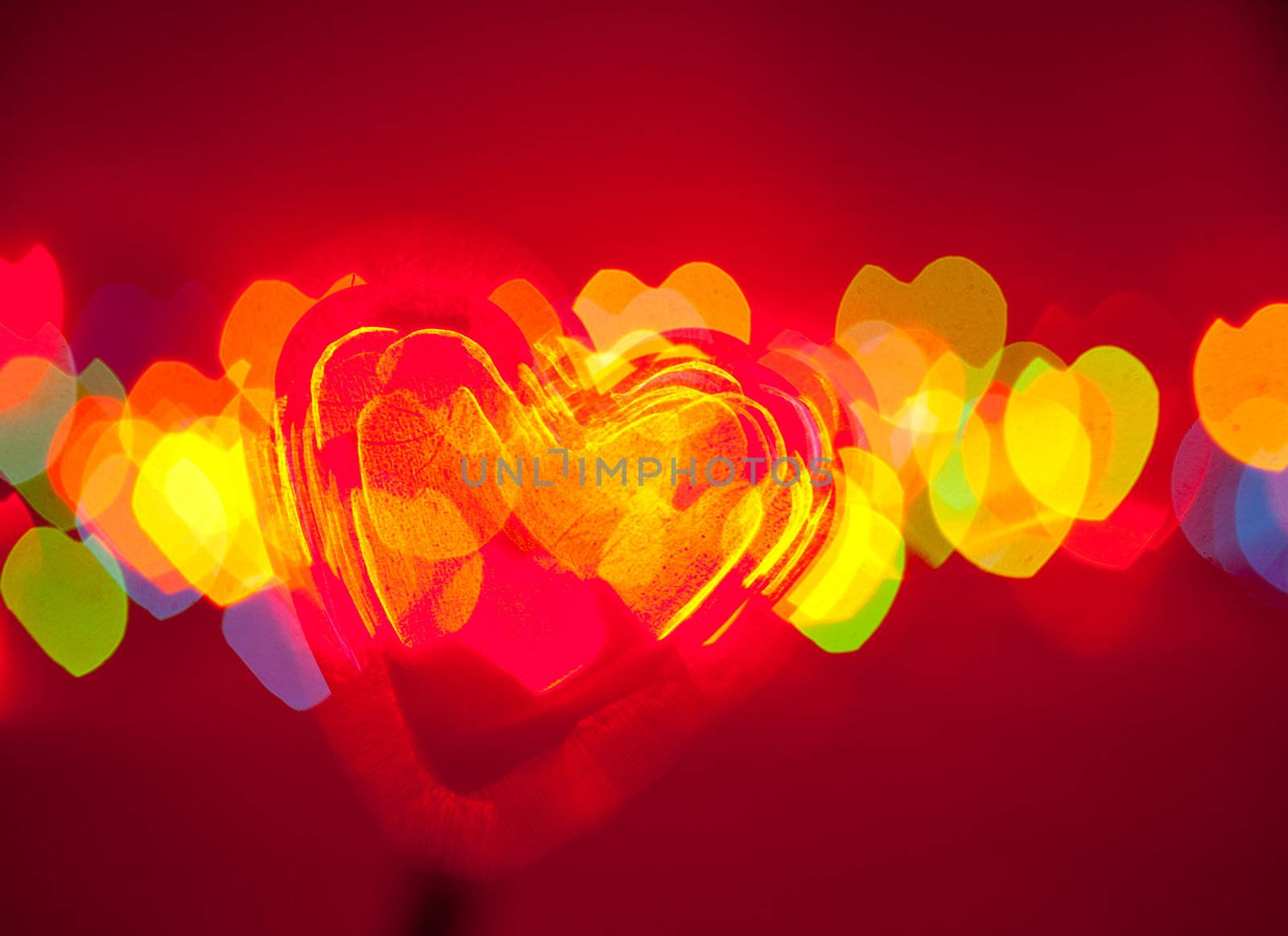 Red transparent plastic heart with blured lights in background, very shallow DOF