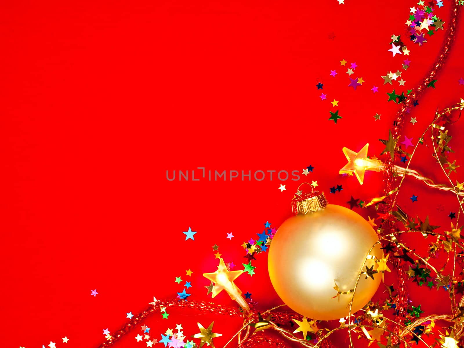 Christmas bauble with star-shaped lights and tinsel on red background, shallow DOF
