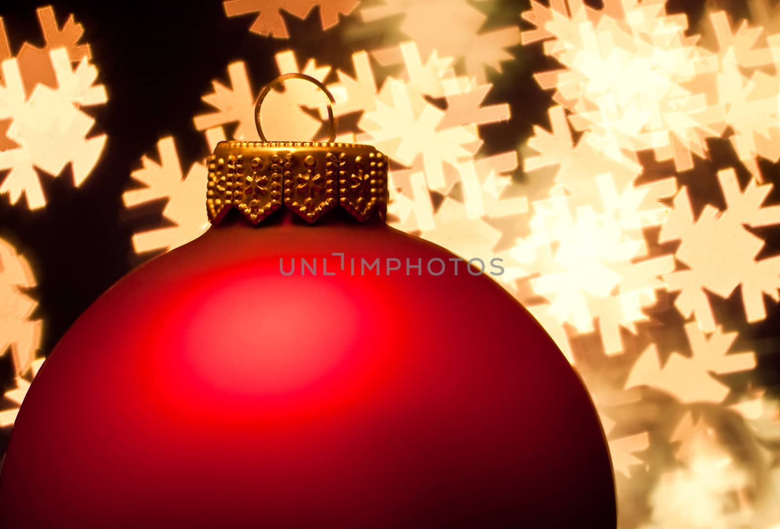 Red Christmas bauble with blured lights in a shape of snowflakes in background, very shallow DOF