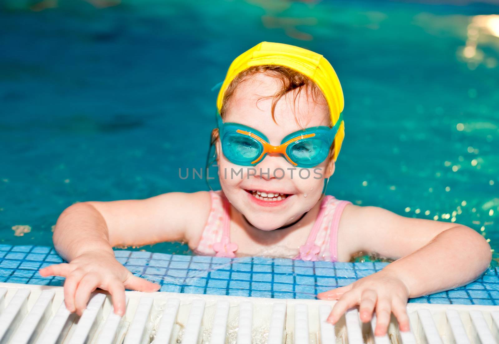 Little girl wearing goggles in a swimming pool