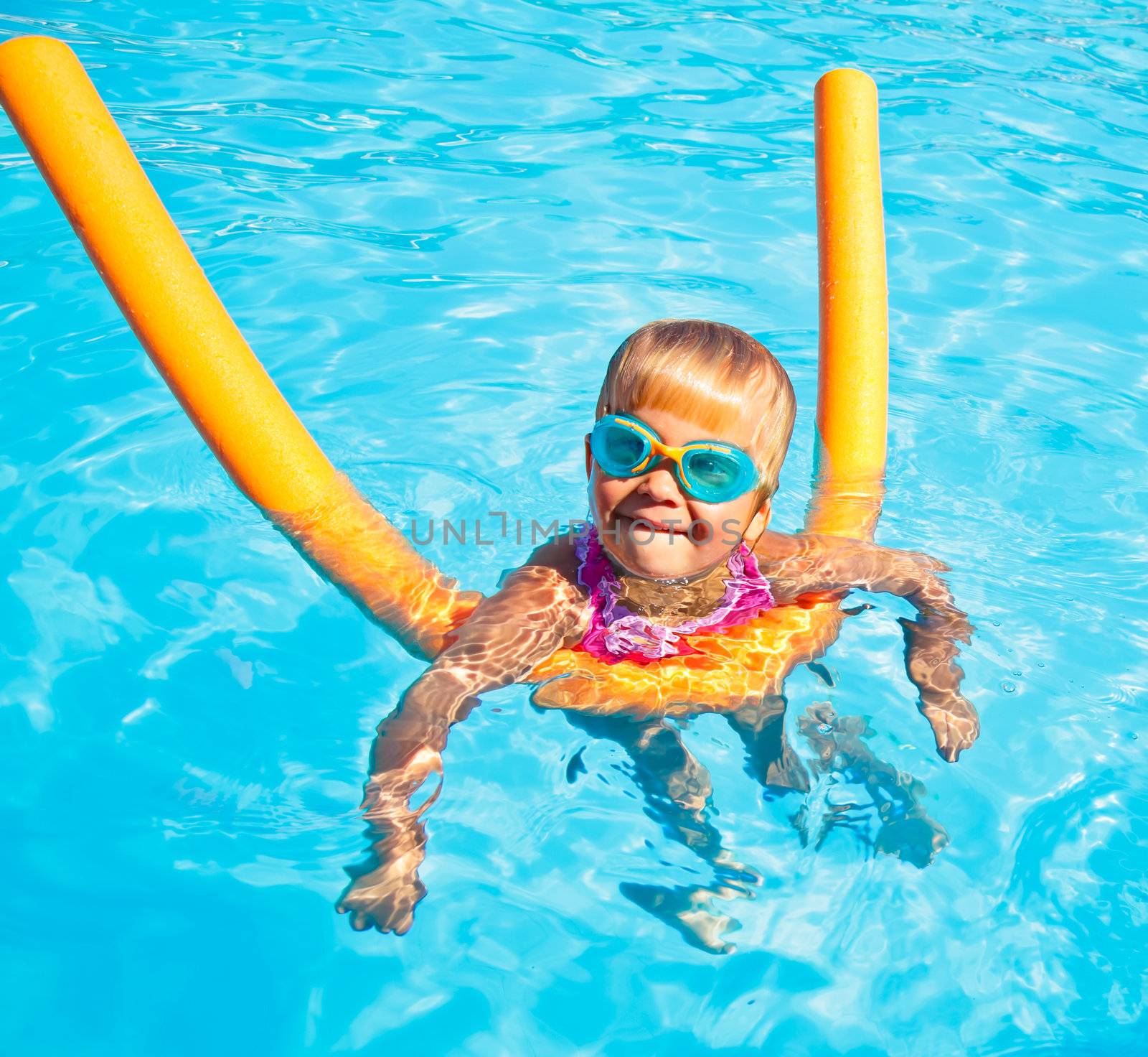 Little girl wearing swimming goggles in a hotel pool