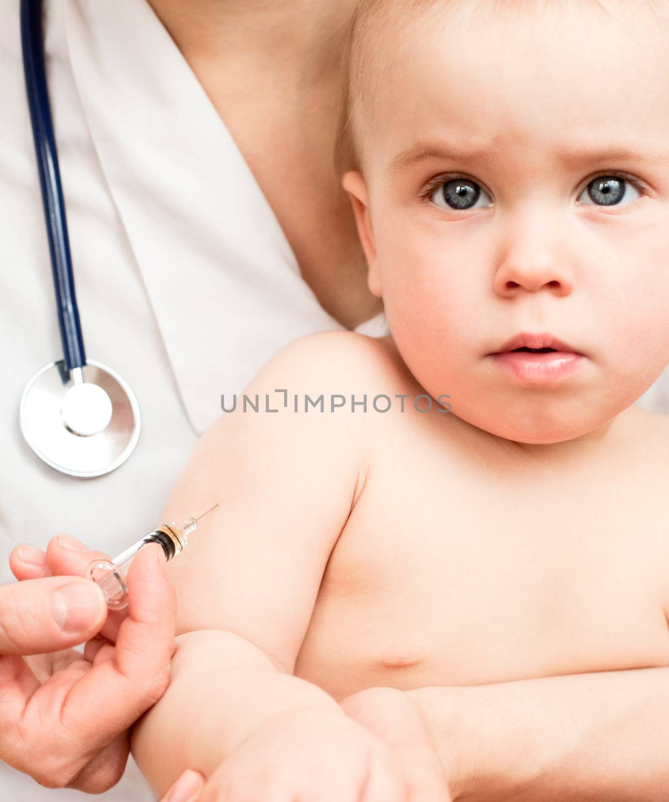 Doctor giving a child an intramuscular injection in arm, shallow DOF