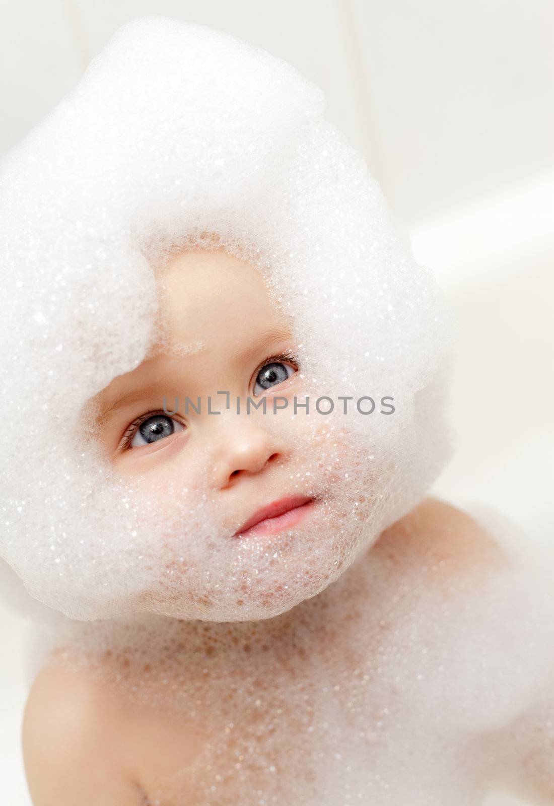 Cute little baby girl bathing in soapsuds