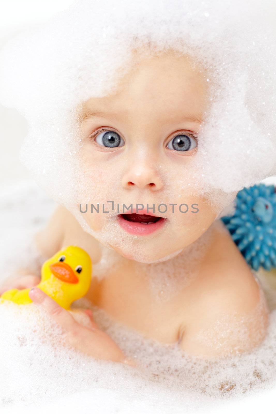 Cute little baby girl bathing in soapsuds