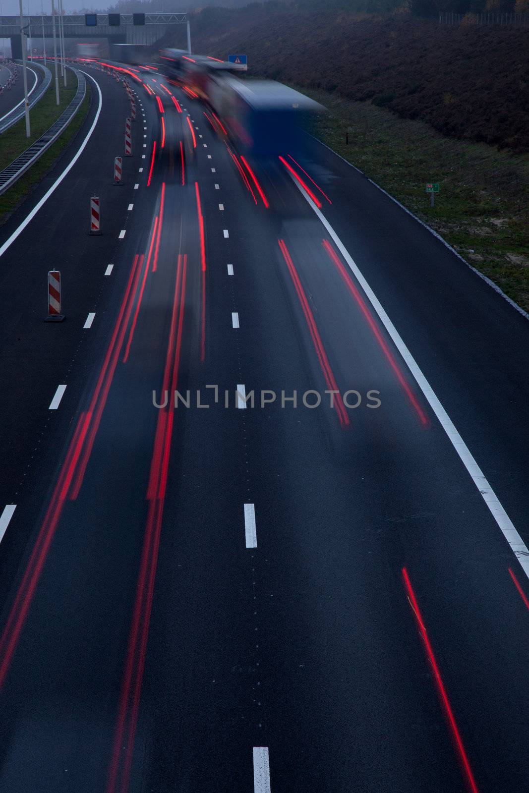 motorway at dusk with traffic of trucks and light trails