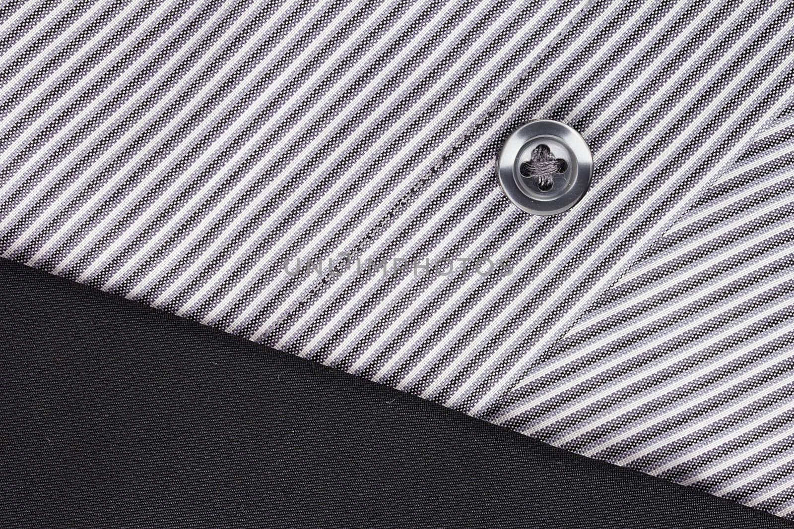 Close-up photograph of a black button on a striped gray pattern.