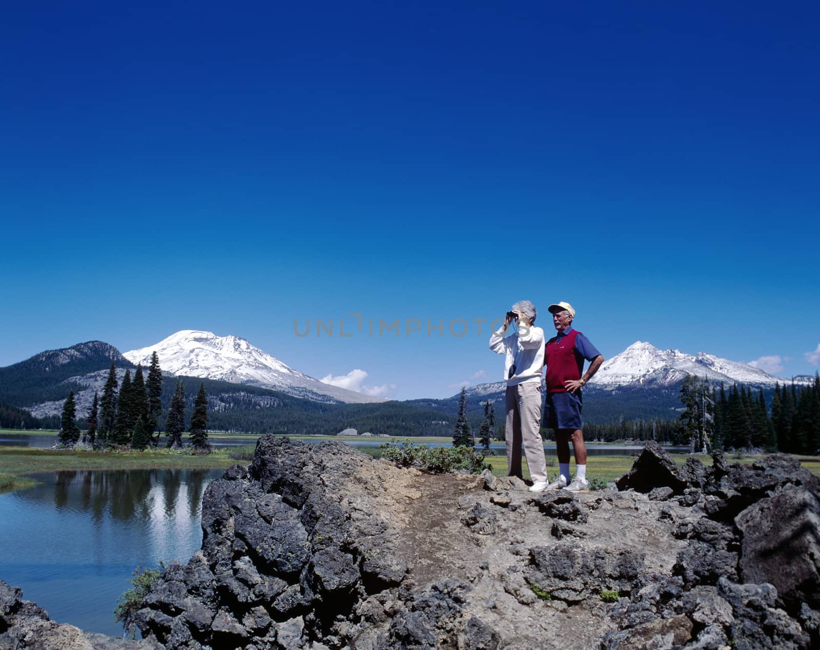 Mountains in Oregon in Cascades range with a lake and a man and a woman in the foreground
