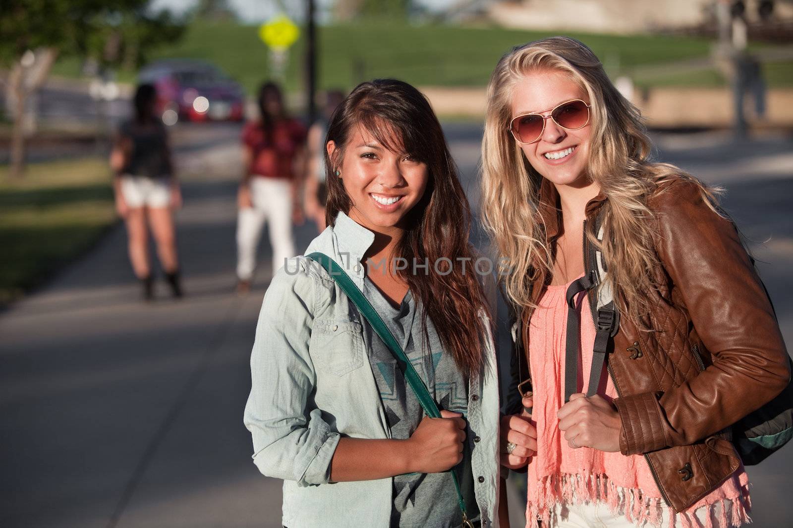 Two smiling teenage female students on school campus