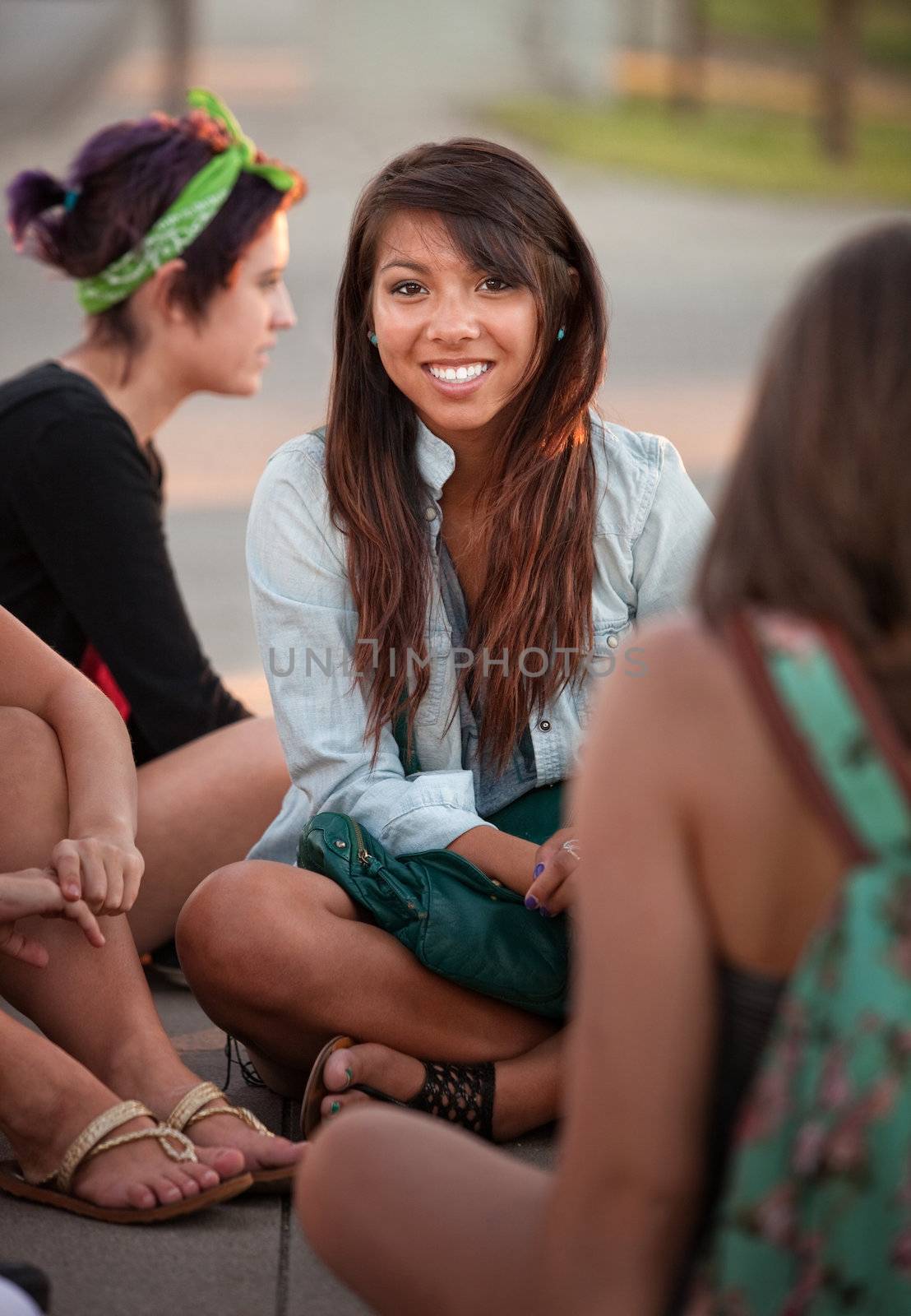 Grinning Filipino girl with friends sitting cross legged 