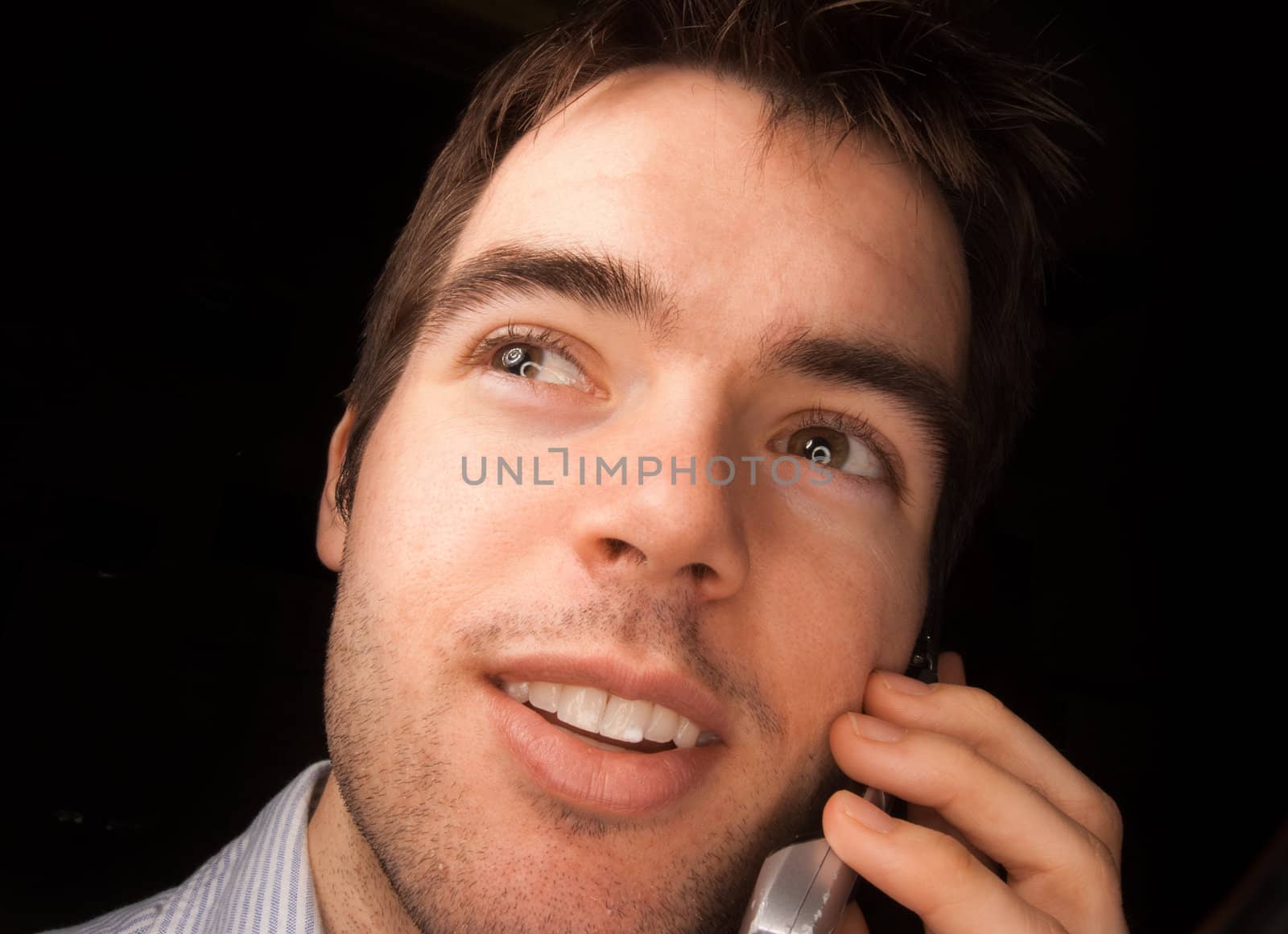 Young man talking on a cell phone, black backgound